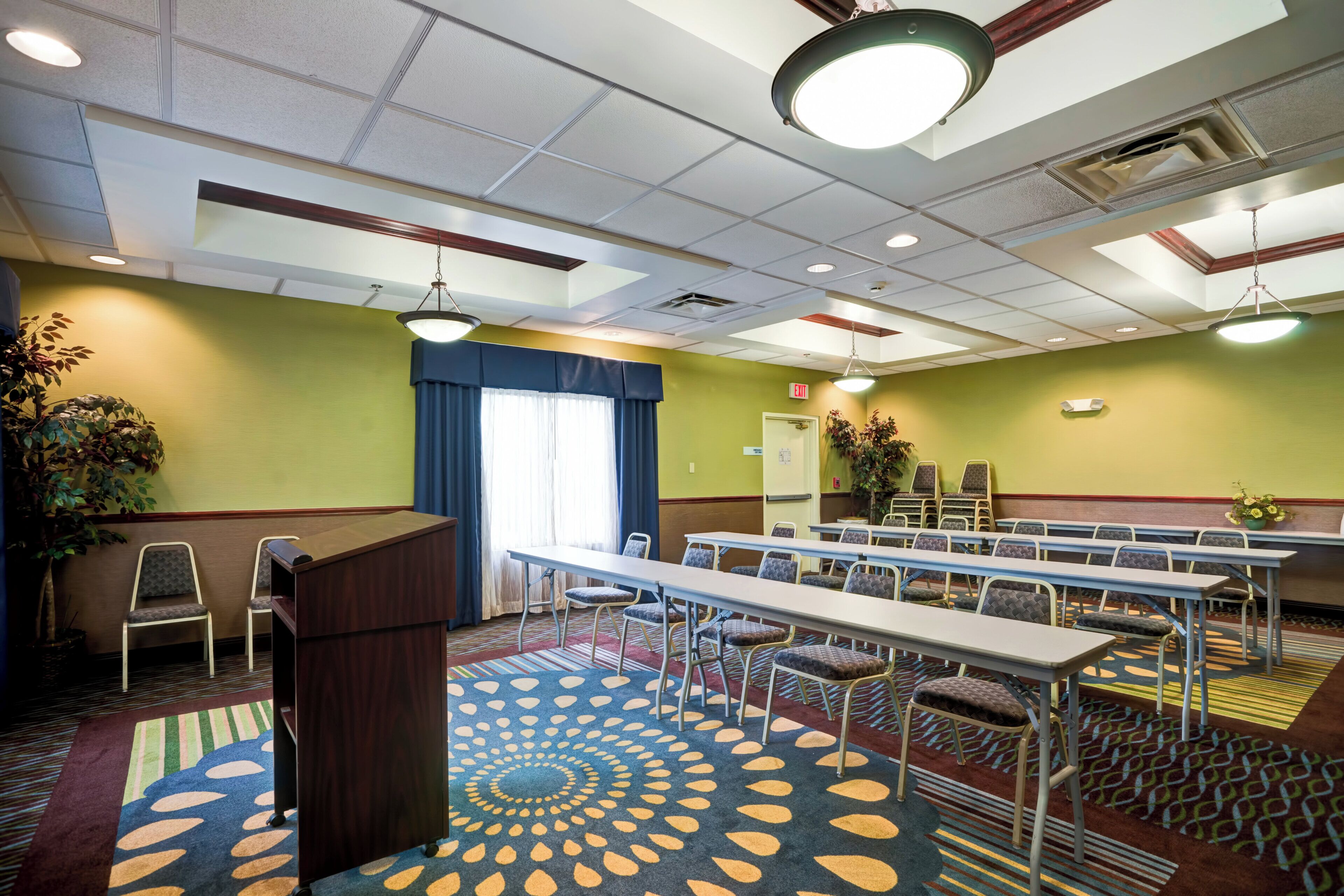 A conference room with a podium, tables, chairs, and a patterned carpet.