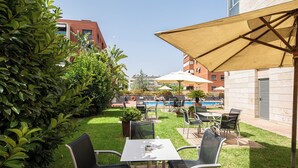 An outdoor patio area with tables and chairs, a pool, and a view of the surrounding buildings. - Sercotel Cornella Barcelona (Cornella de Llobregat)