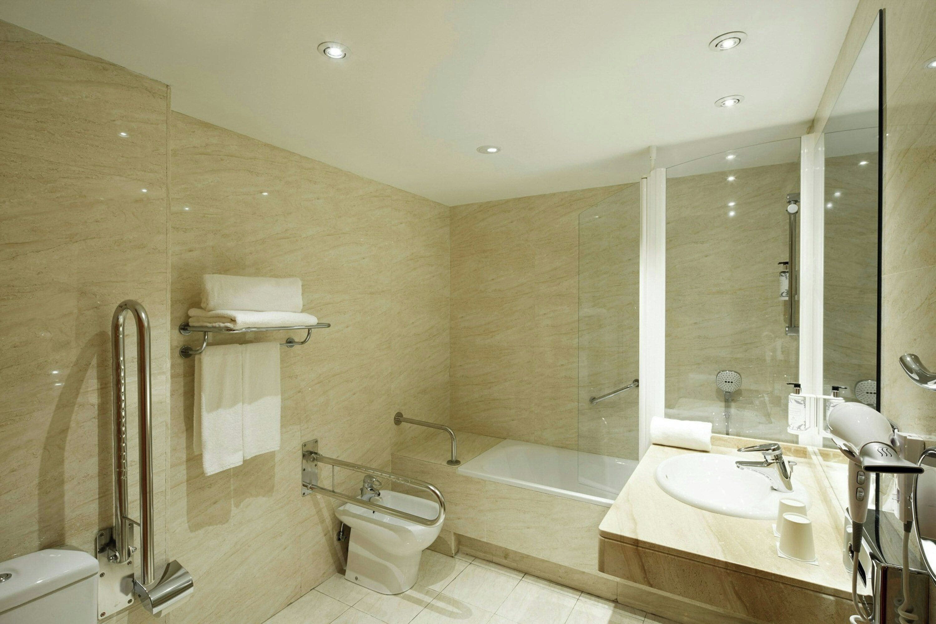 Un baño moderno con bañera, ducha, inodoro y lavamanos.