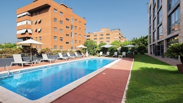 Una piscina al aire libre de temporada, sombrillas, tumbonas
