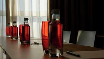Una mesa de conferencias con varias botellas de vidrio y vasos rojos.