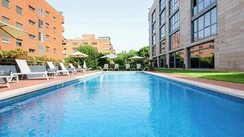 Una piscina al aire libre de temporada, sombrillas, tumbonas