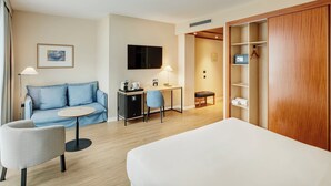 A hotel room with a bed, a sofa, a desk, a chair, a TV, and a wardrobe. - Sercotel Cornella Barcelona (Cornella de Llobregat)