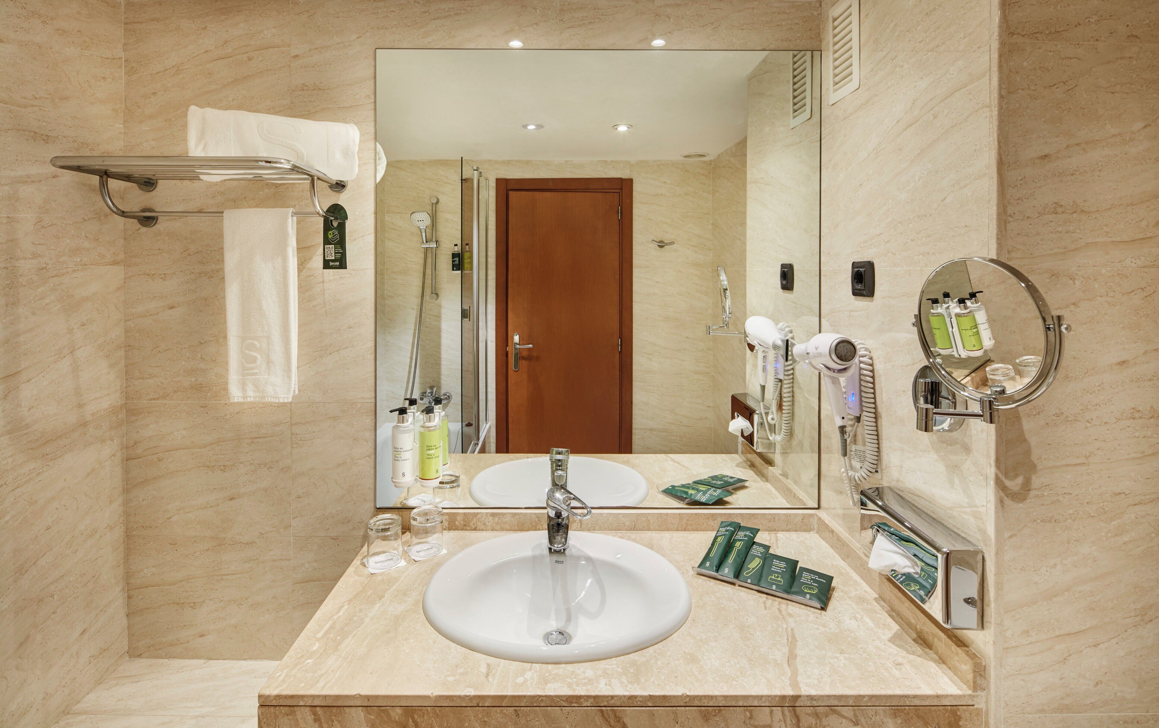 A bathroom with a large mirror, a sink, and a shower area.