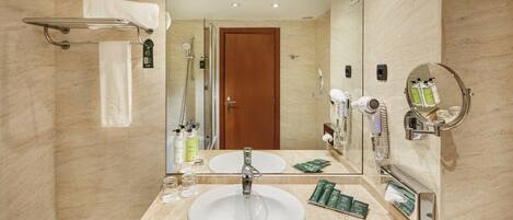 A bathroom with a large mirror, a sink, and a shower area.