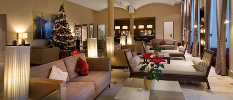 A spacious living area with a large Christmas tree, comfortable seating, and a modern bar area.