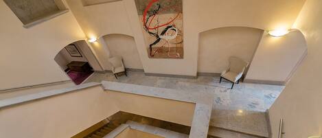 Un interior de varios niveles con una escalera central, dos zonas de estar y un gran cuadro abstracto en la pared.