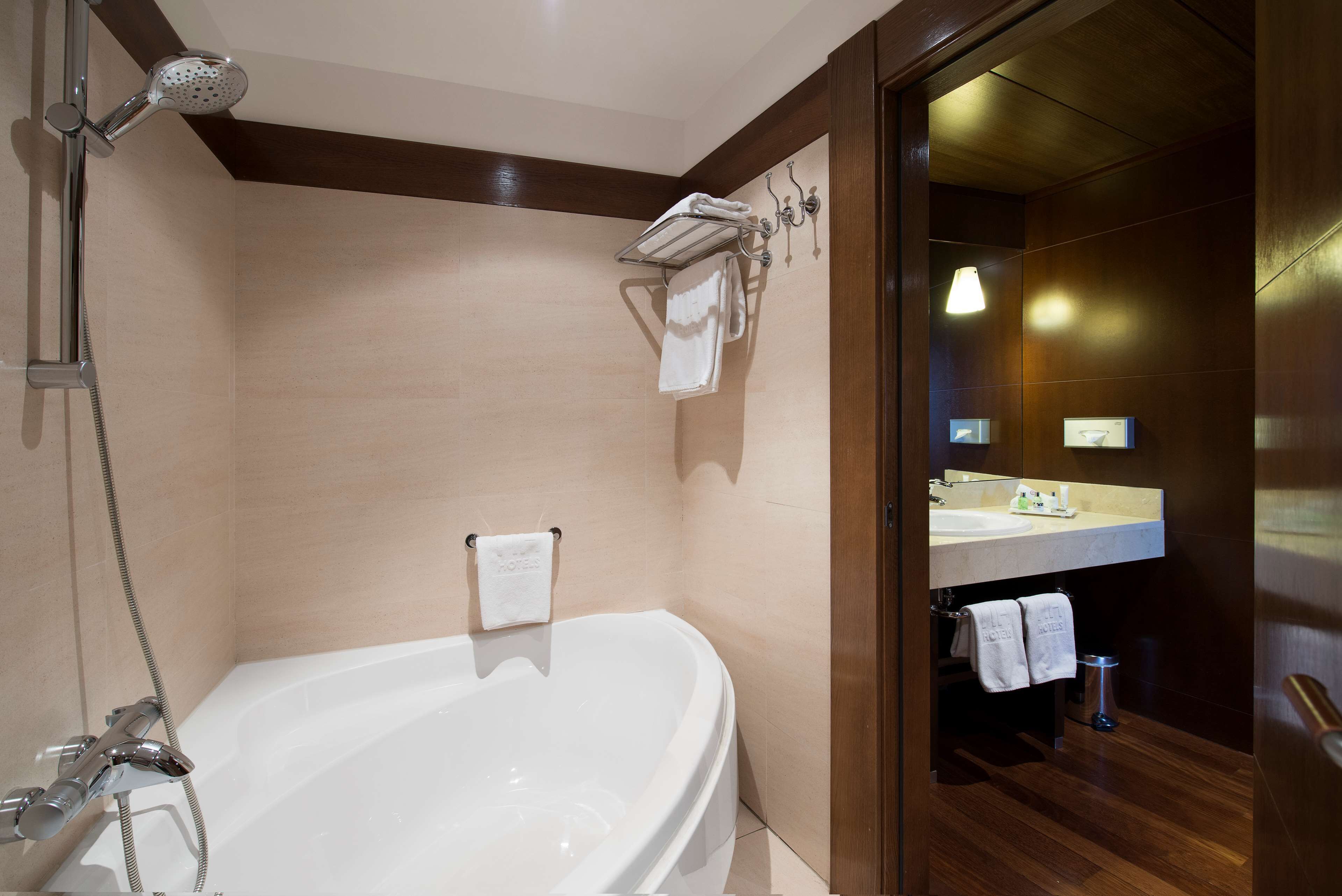 A modern bathroom with a freestanding bathtub, a showerhead, and a vanity with a mirror and sink.
