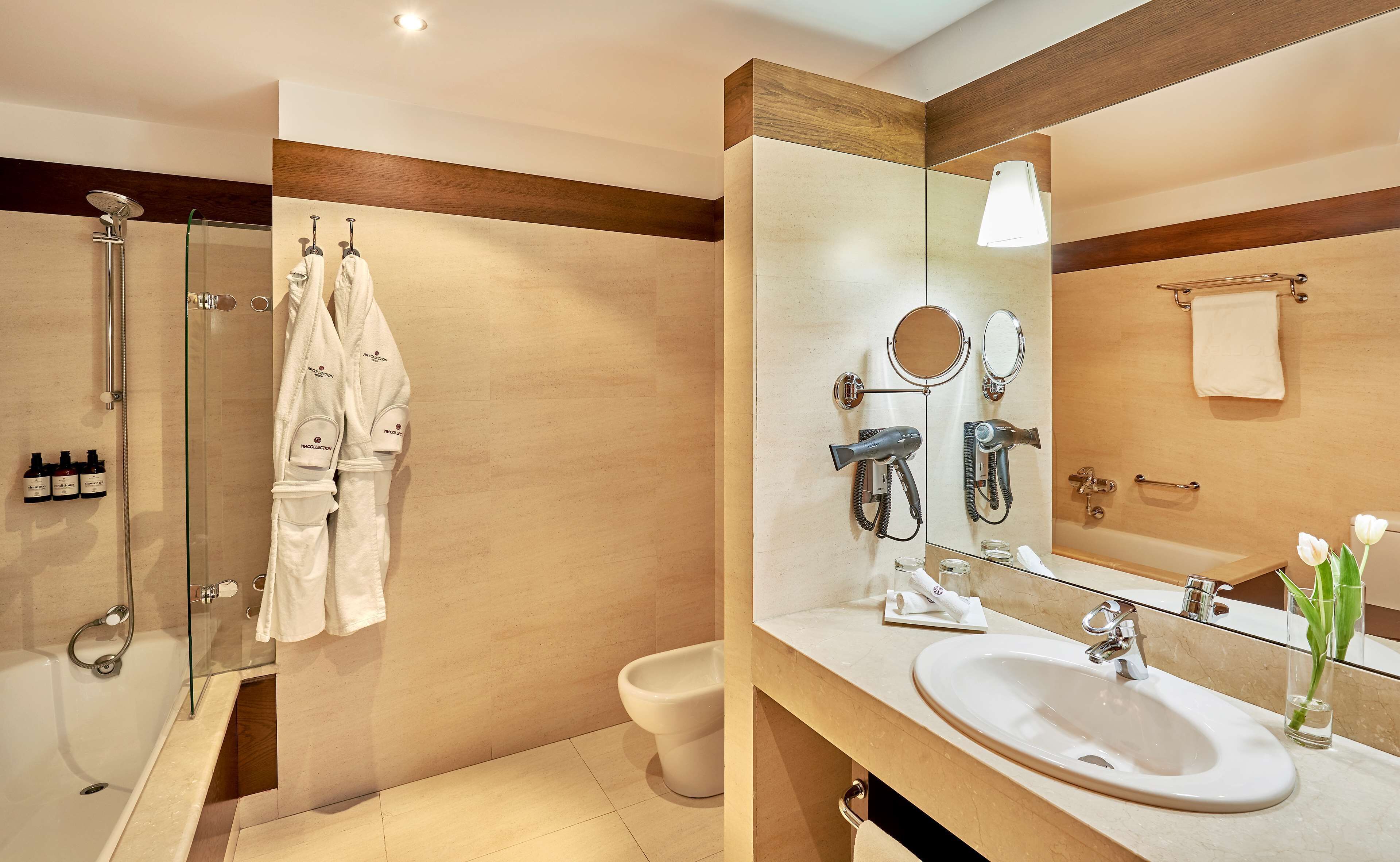 Un baño moderno con ducha envuelta en vidrio, un espejo grande, un lavabo y un inodoro.