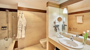 A modern bathroom with a glass-enclosed shower, a large mirror, a sink, and a toilet.