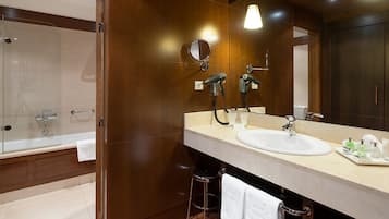 A modern bathroom with a glass-enclosed shower, a large mirror, and a vanity with a sink and toiletries.