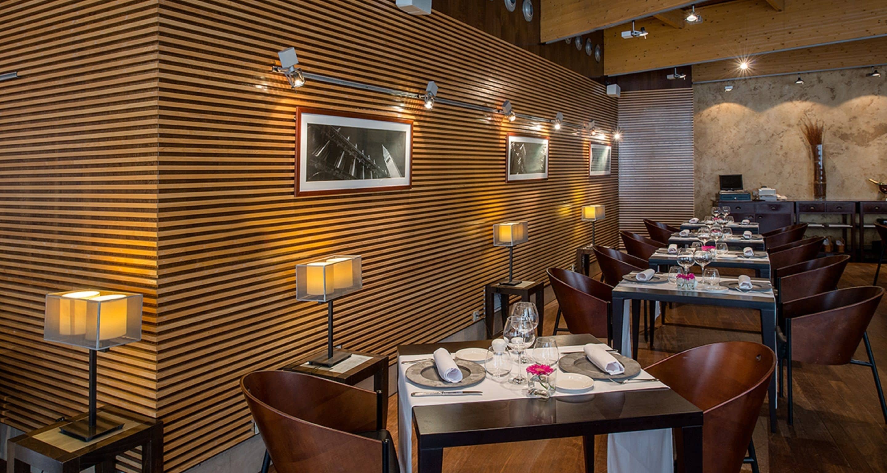 Un restaurante con paneles de madera, cuadros enmarcados y mesas dispuestas para comer.