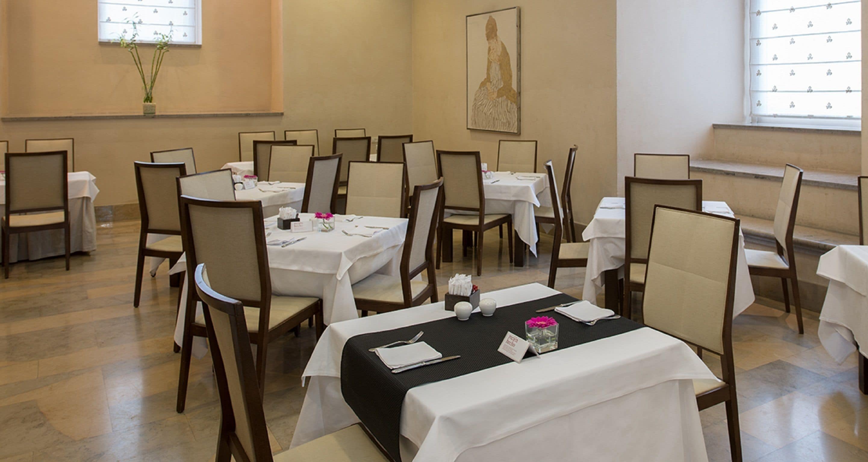 A dining area with multiple tables and chairs, arranged in rows.