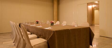 A conference room with a long table, chairs, and floral centerpieces.