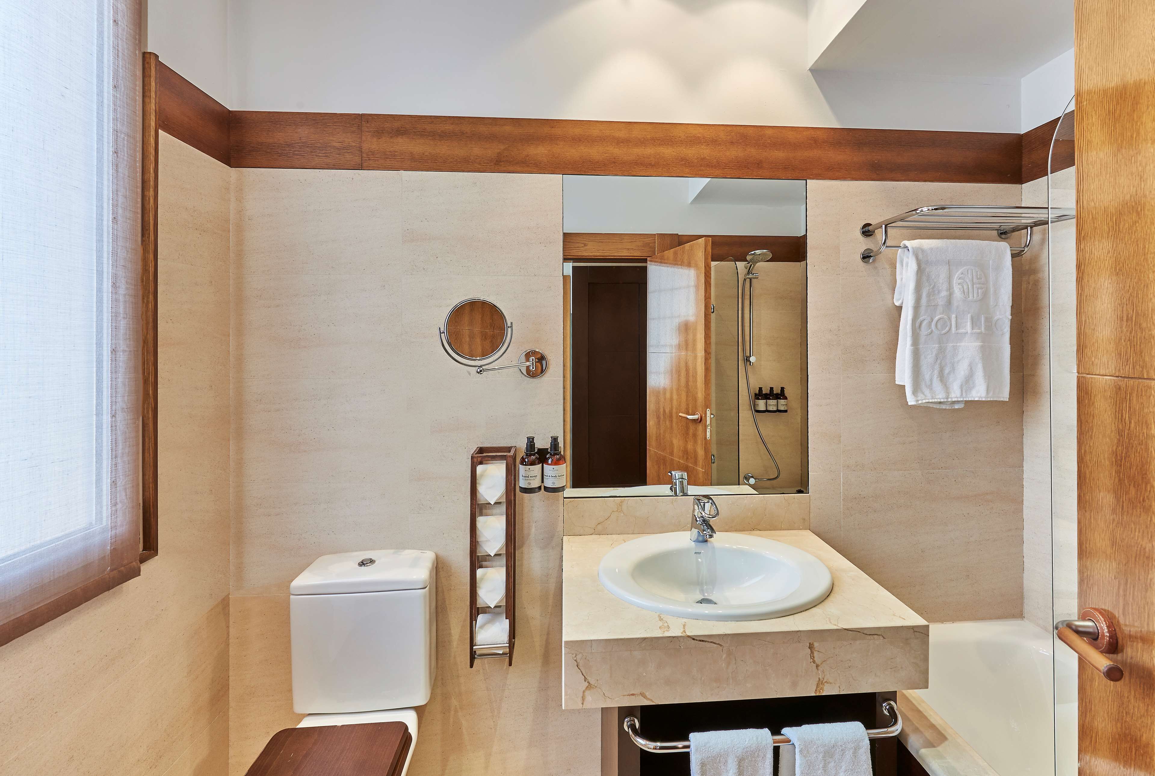 A modern bathroom with a toilet, sink, mirror, and shower.
