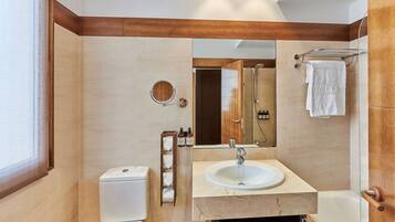 A modern bathroom with a toilet, sink, mirror, and shower.
