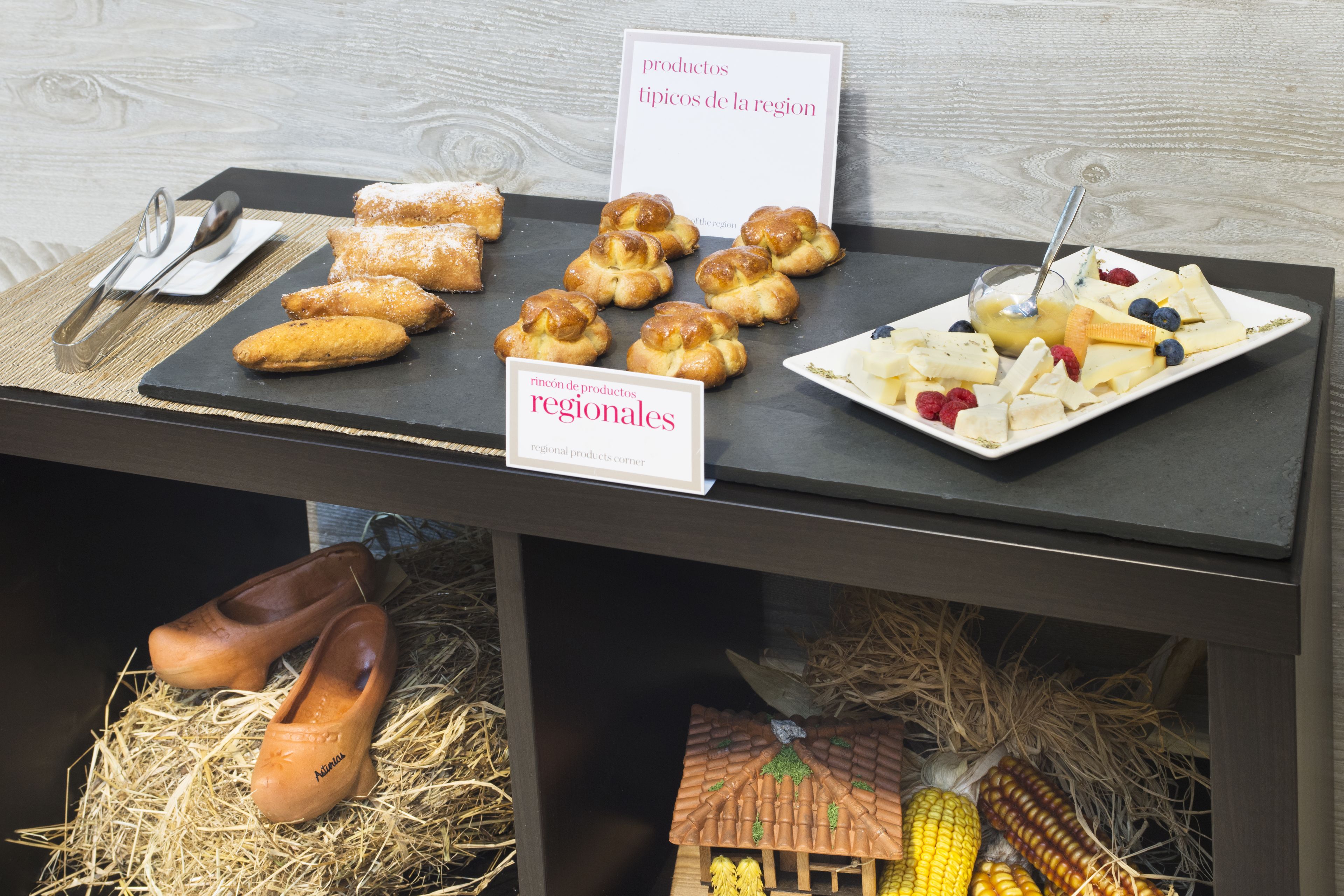 Exhibición de productos regionales, incluyendo pasteles, frutas y una maqueta de una casa.