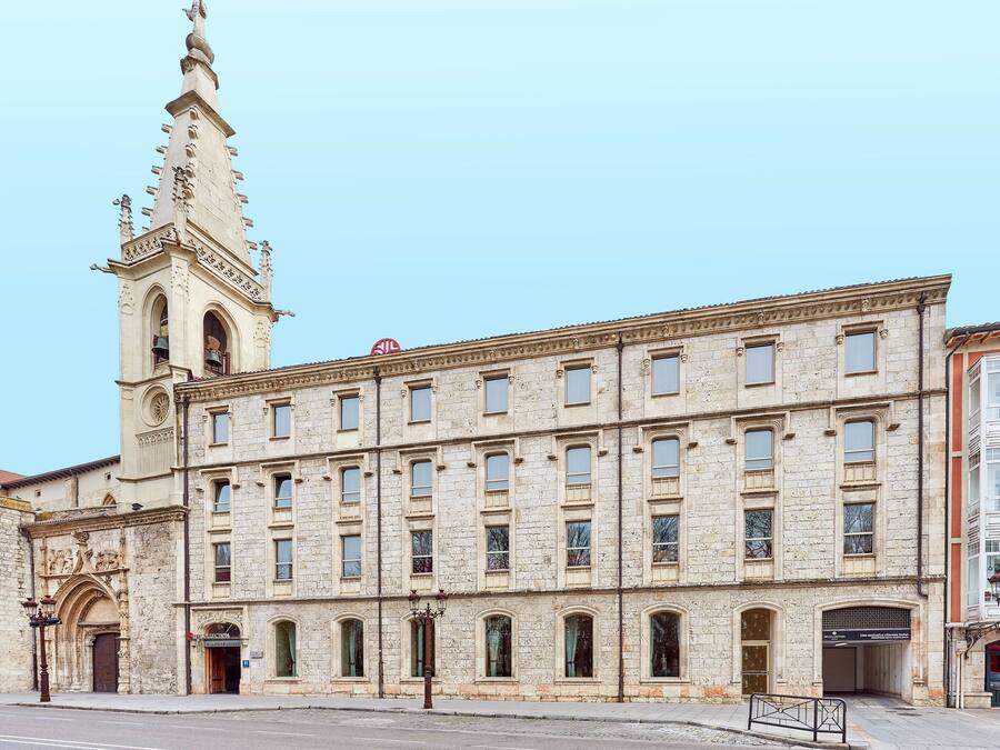 A historic building with a prominent tower, multiple windows, and a street lamp.