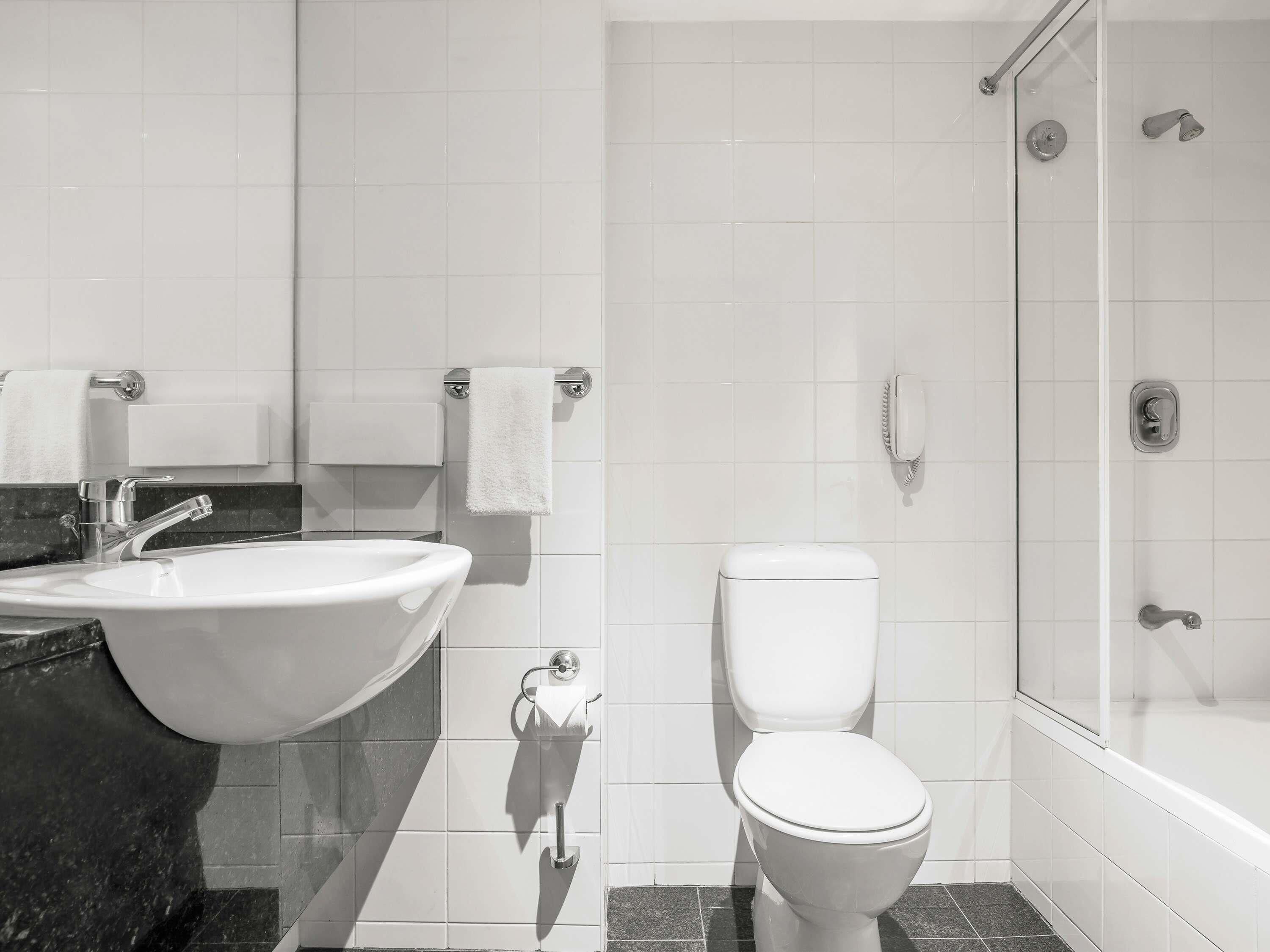 Une salle de bain moderne équipée d’un lavabo, de toilettes et d’une douche.