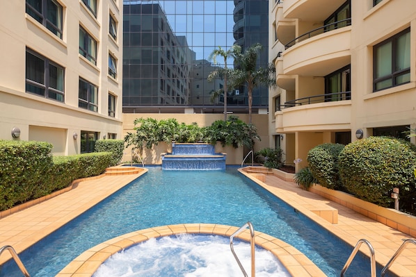 Una piscina al aire libre, sillones reclinables de piscina