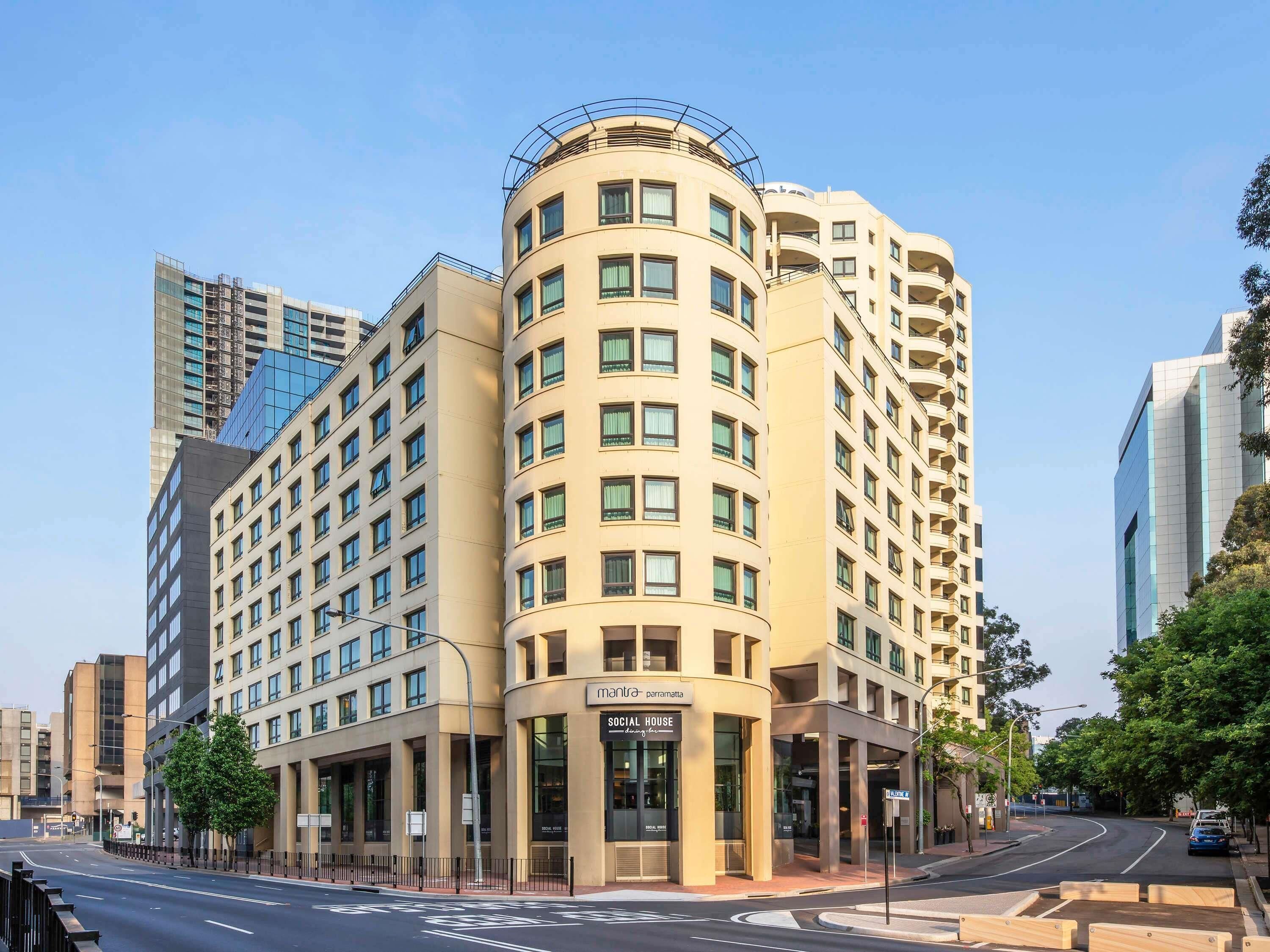 Un hôtel à plusieurs étages, doté d’une façade incurvée, de grandes fenêtres et d’une enseigne indiquant « mantra - Parramatta ».
