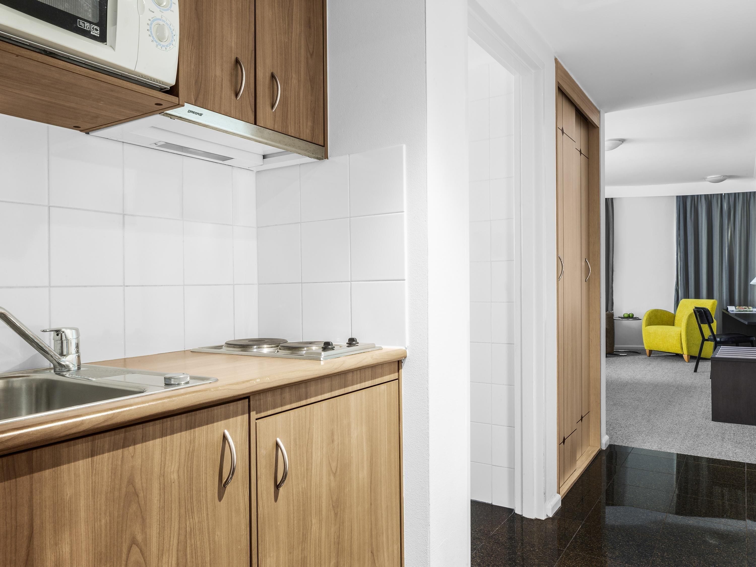 A modern kitchen with wooden cabinets, a stainless steel sink, and a microwave.