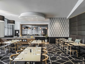Un restaurante moderno con una isla central, varias zonas de estar y una pared decorada con un diseño.