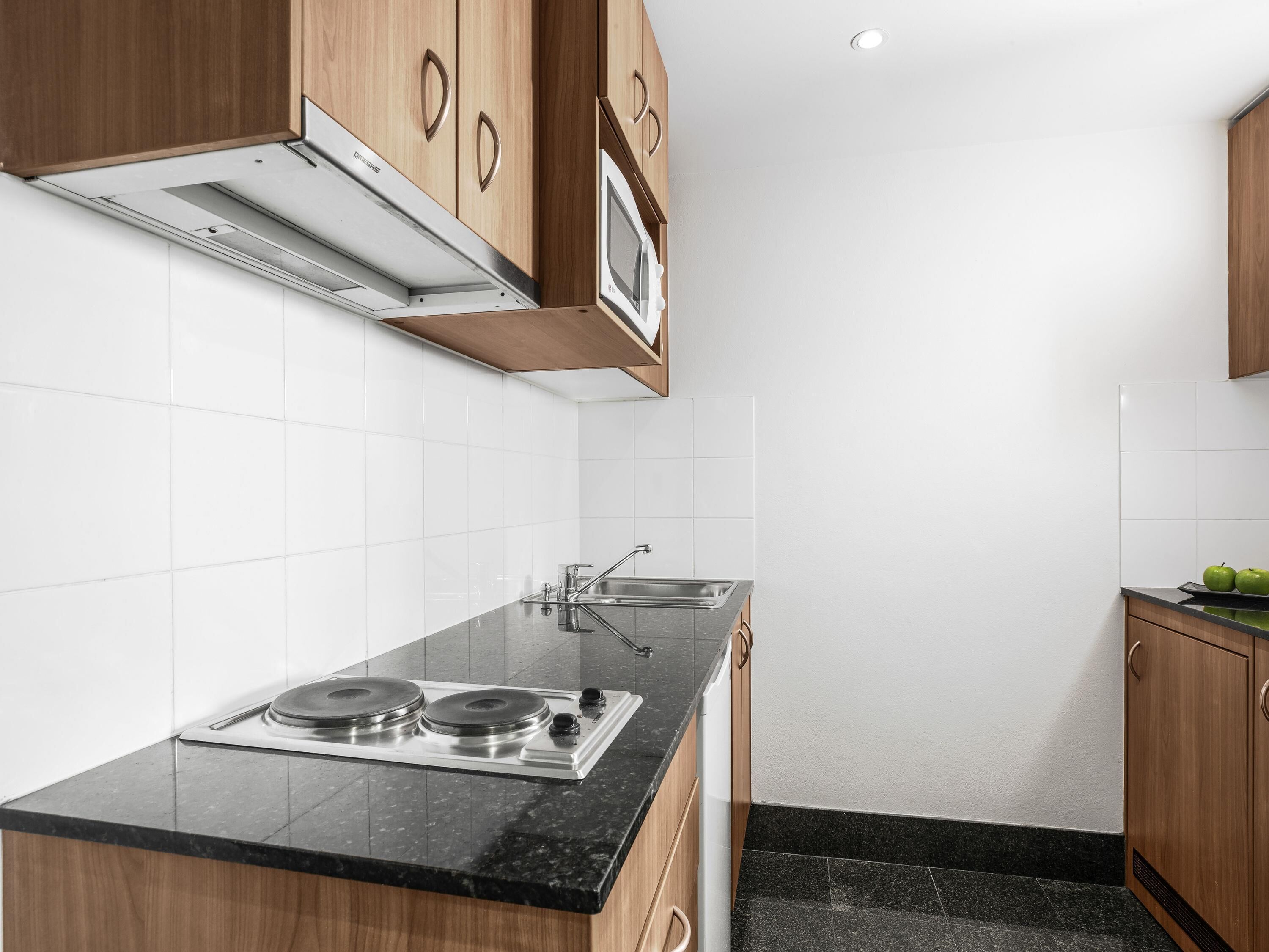 A kitchen with a stove, sink, and wooden cabinets.