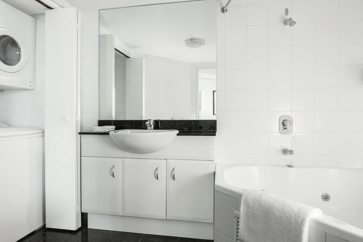 A modern bathroom with a white sink, a large mirror, a toilet, and a bathtub.