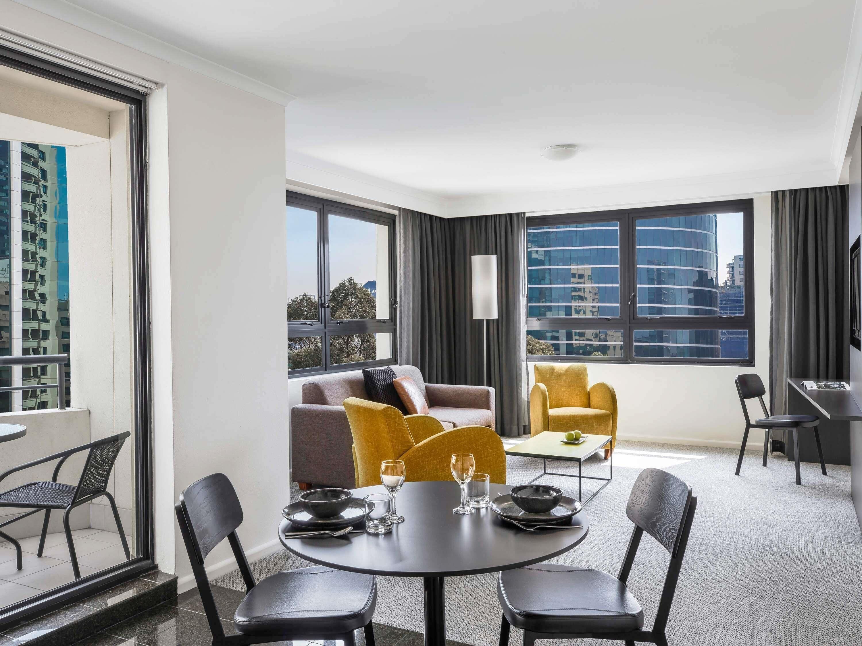 Een moderne hotelkamer met een zithoek, een bank en uitzicht op de stad.