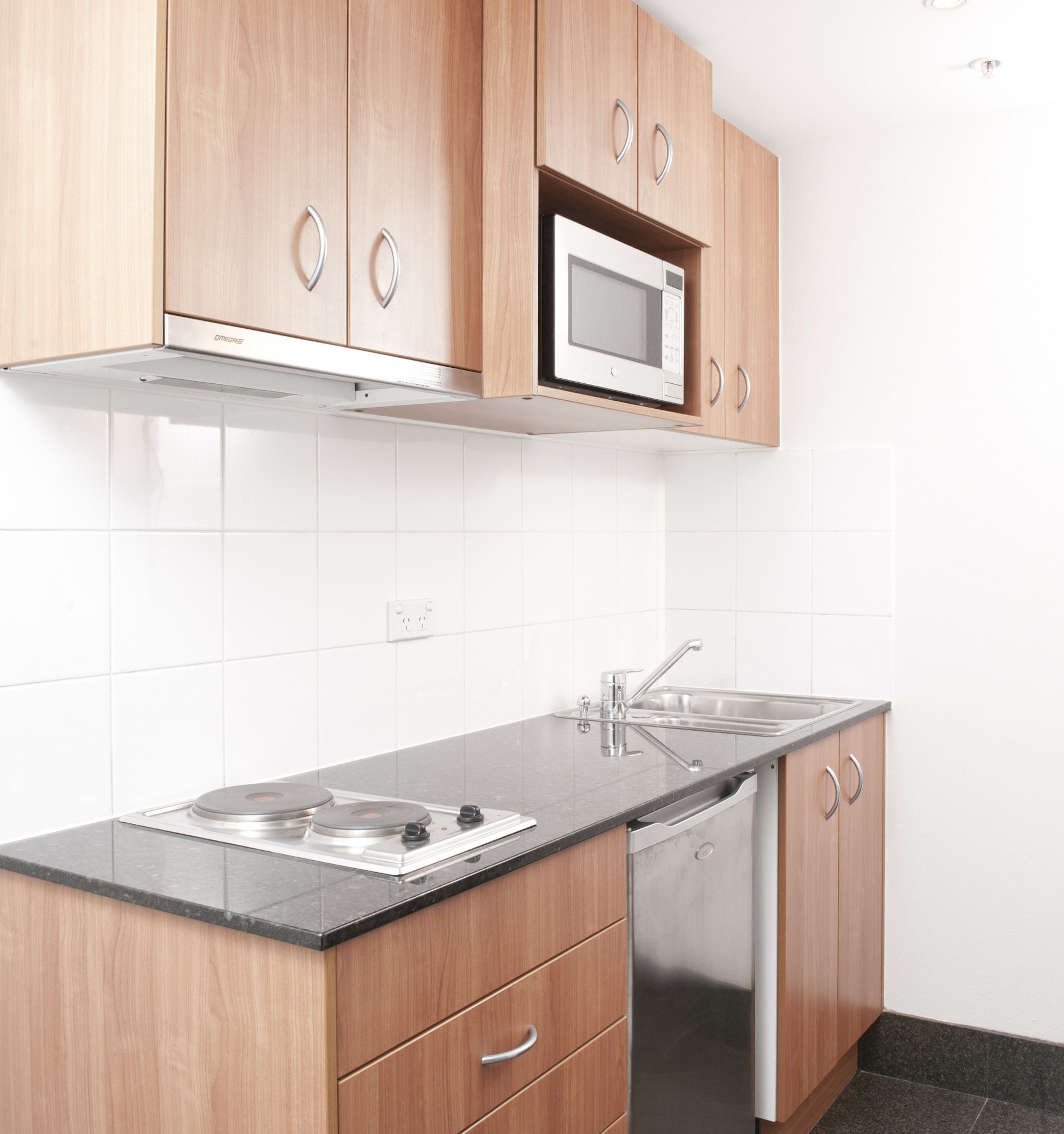 A modern kitchen with wooden cabinets, a built-in microwave, stainless steel sink, and a dishwasher.