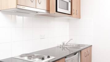 A modern kitchen with wooden cabinets, a built-in microwave, stainless steel sink, and a dishwasher.