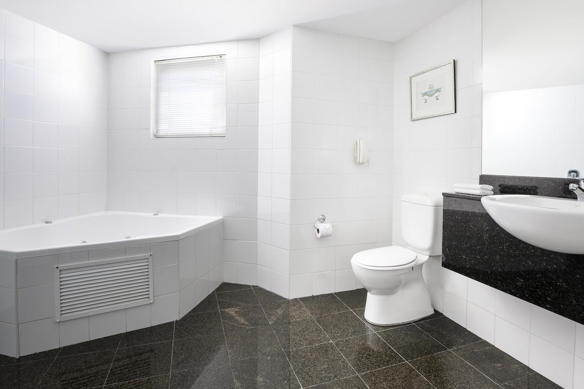 A modern bathroom with a bathtub, toilet, and sink.