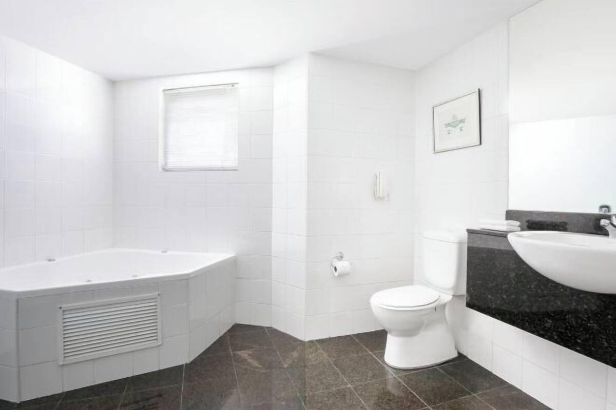 Une salle de bain moderne équipée d’une baignoire, de toilettes et d’un lavabo.