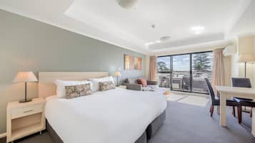 A hotel room with a large bed, a desk, and a view of the outdoors.
