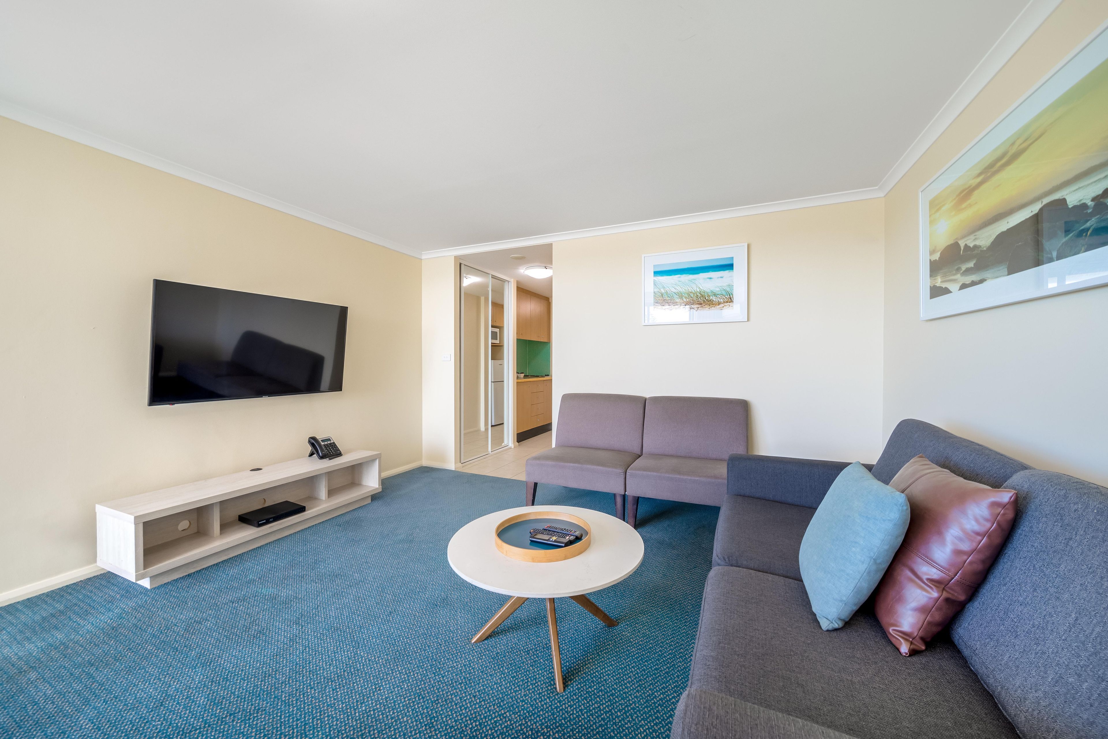 A living room with a flat-screen TV, a sofa, a coffee table, and a small side table.