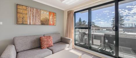 Una sala de estar moderna con un sofá gris, una mesa de centro y un ventanal con vista a la ciudad.