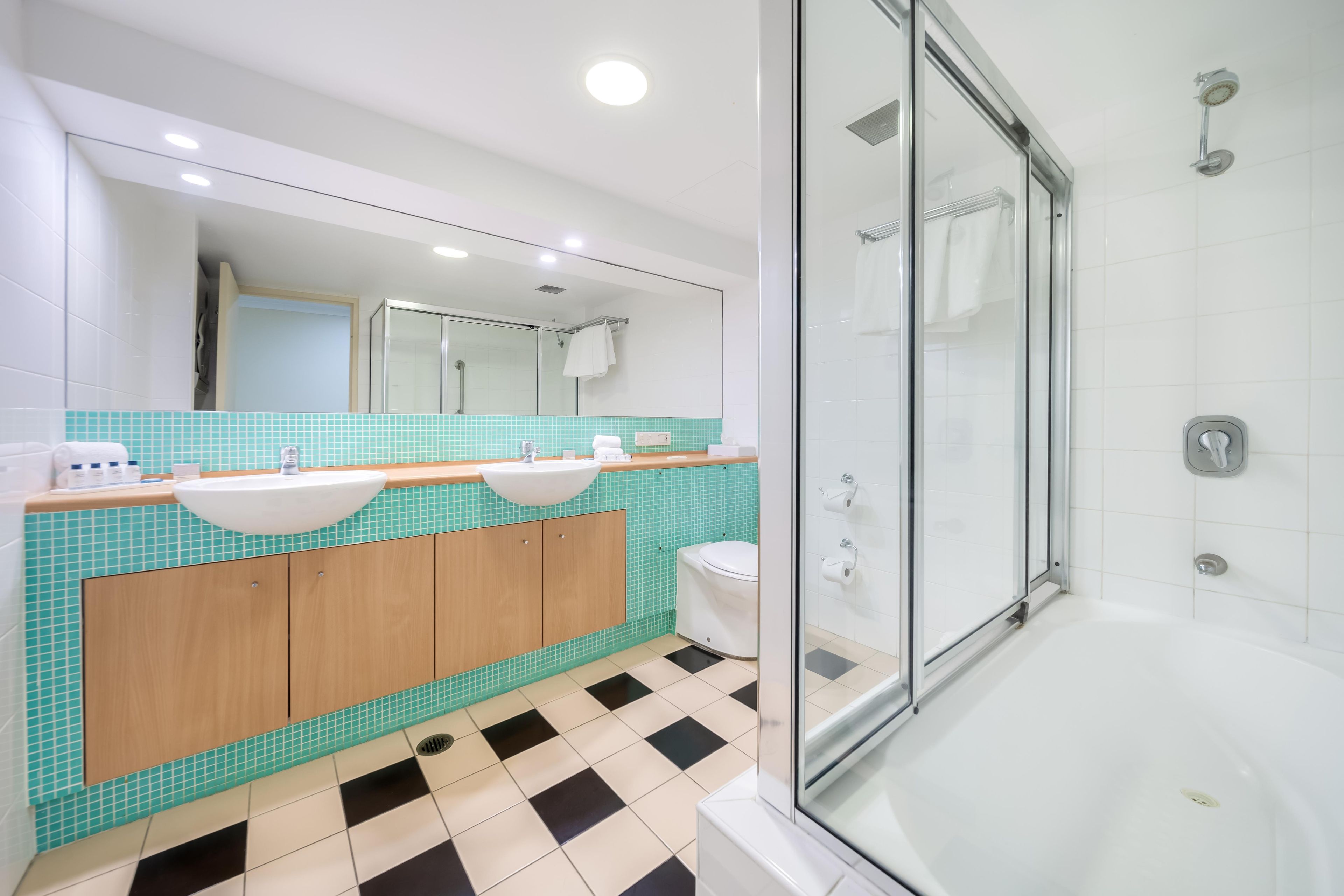 Un baño moderno con cabina de ducha de vidrio, un lavabo blanco y un inodoro.