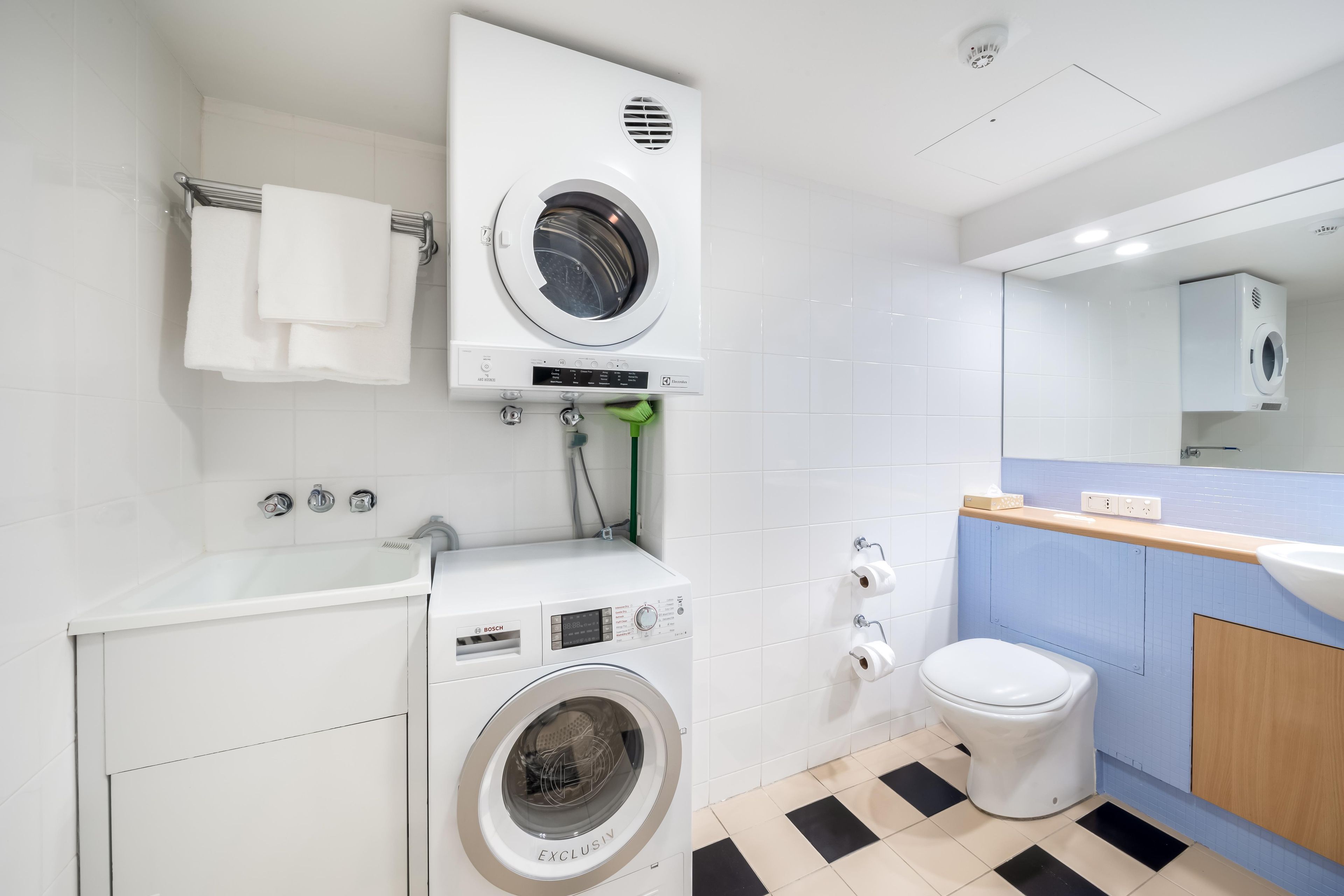 A compact, modern bathroom with a washing machine, a toilet, and a sink.