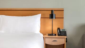 Ett hotellrum med en säng, ett nattduksbord, en lampa och en telefon.