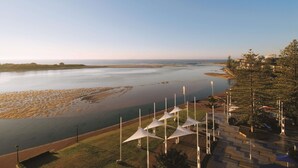 Vista costera con playa, río y una fila de tiendas blancas.