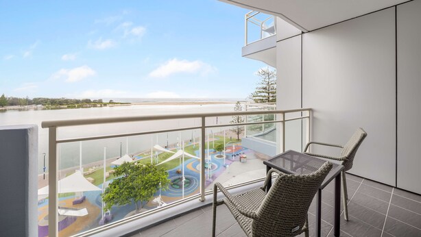 Un balcón con vistas a un cuerpo de agua y una zona de juegos infantiles.