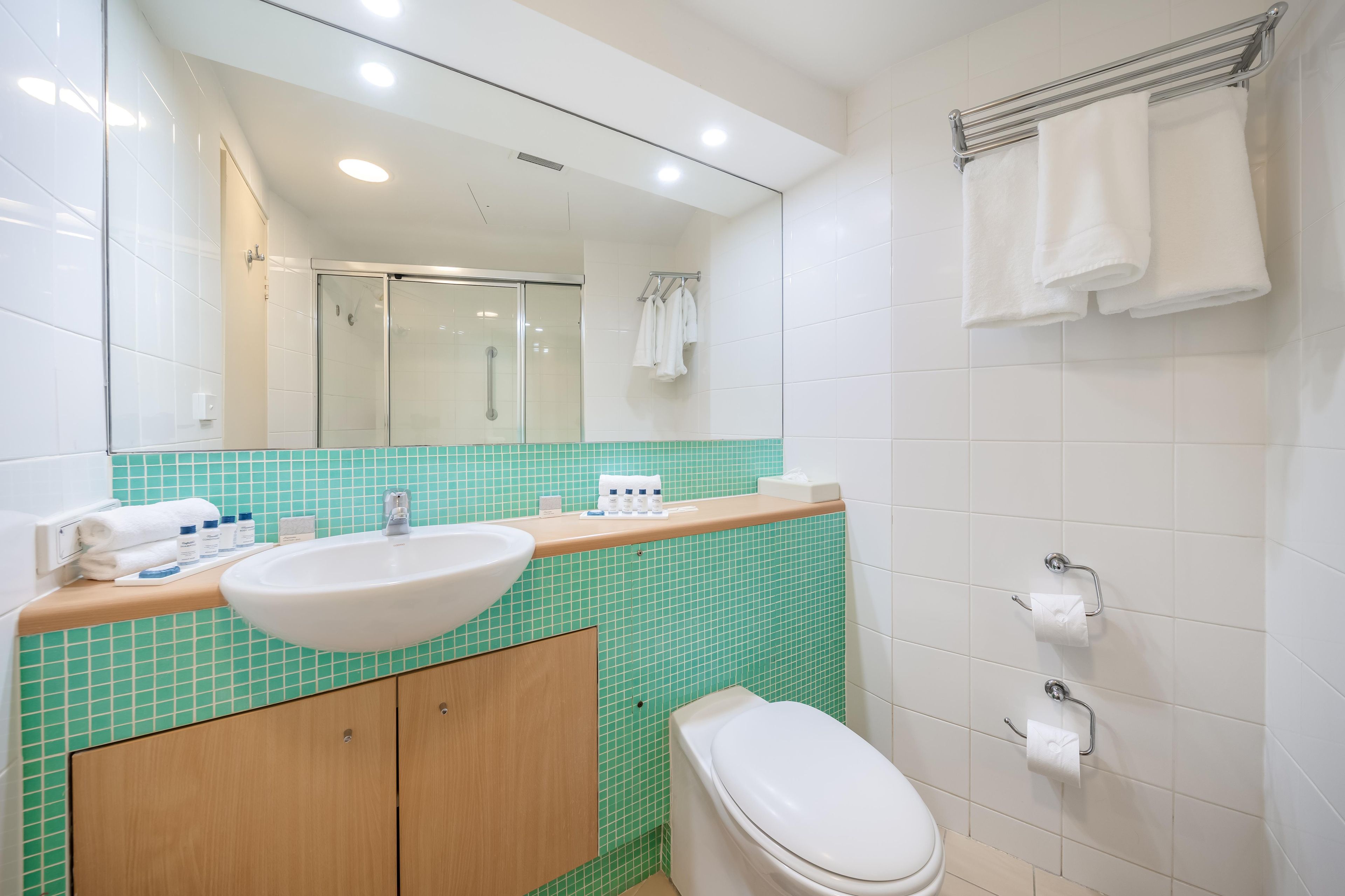 Un baño moderno con lavamanos, espejo y retrete.
