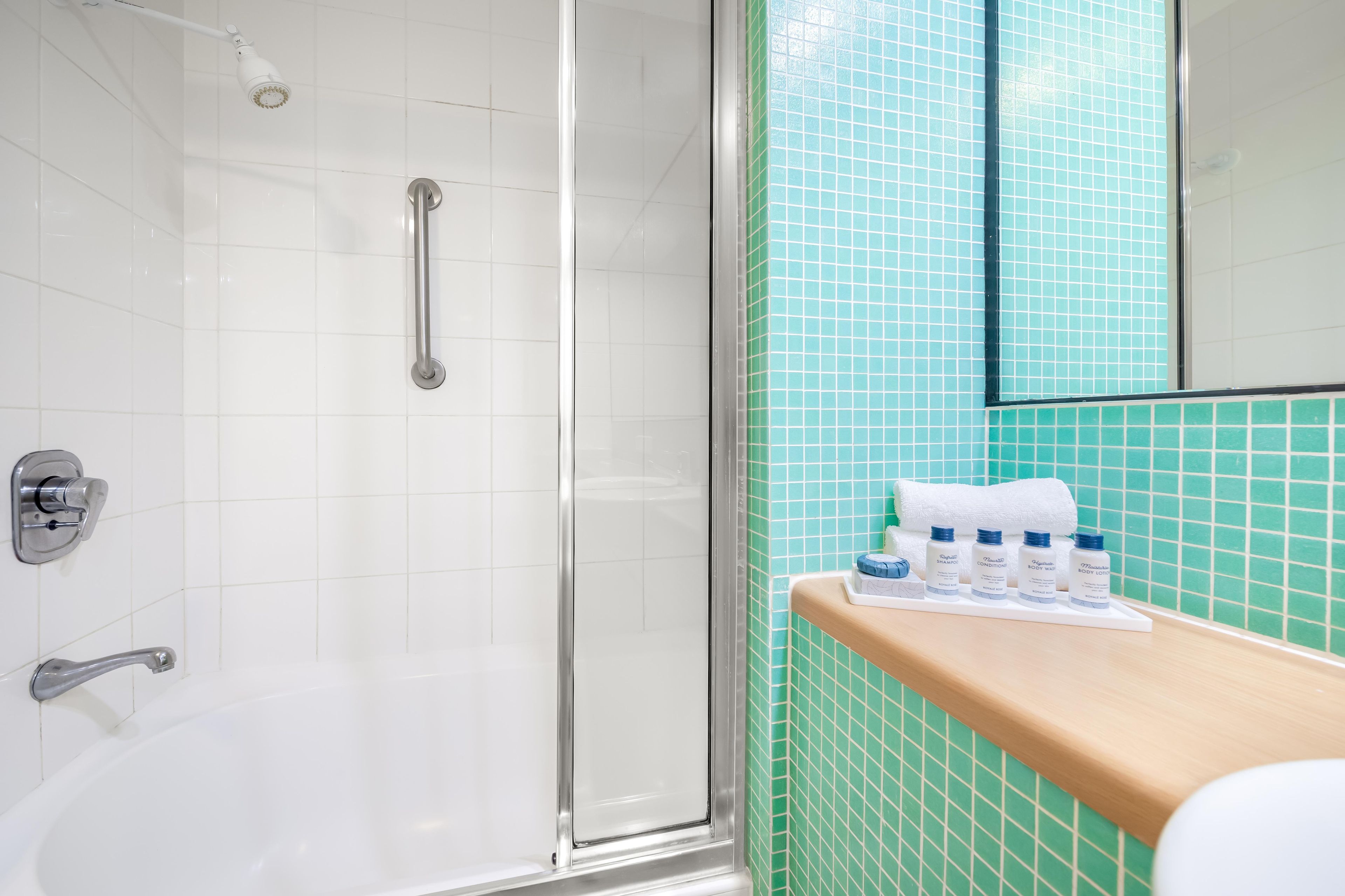 Een badkamer met een douchecabine van glas, een witte badkuip en een wastafel met toiletartikelen.