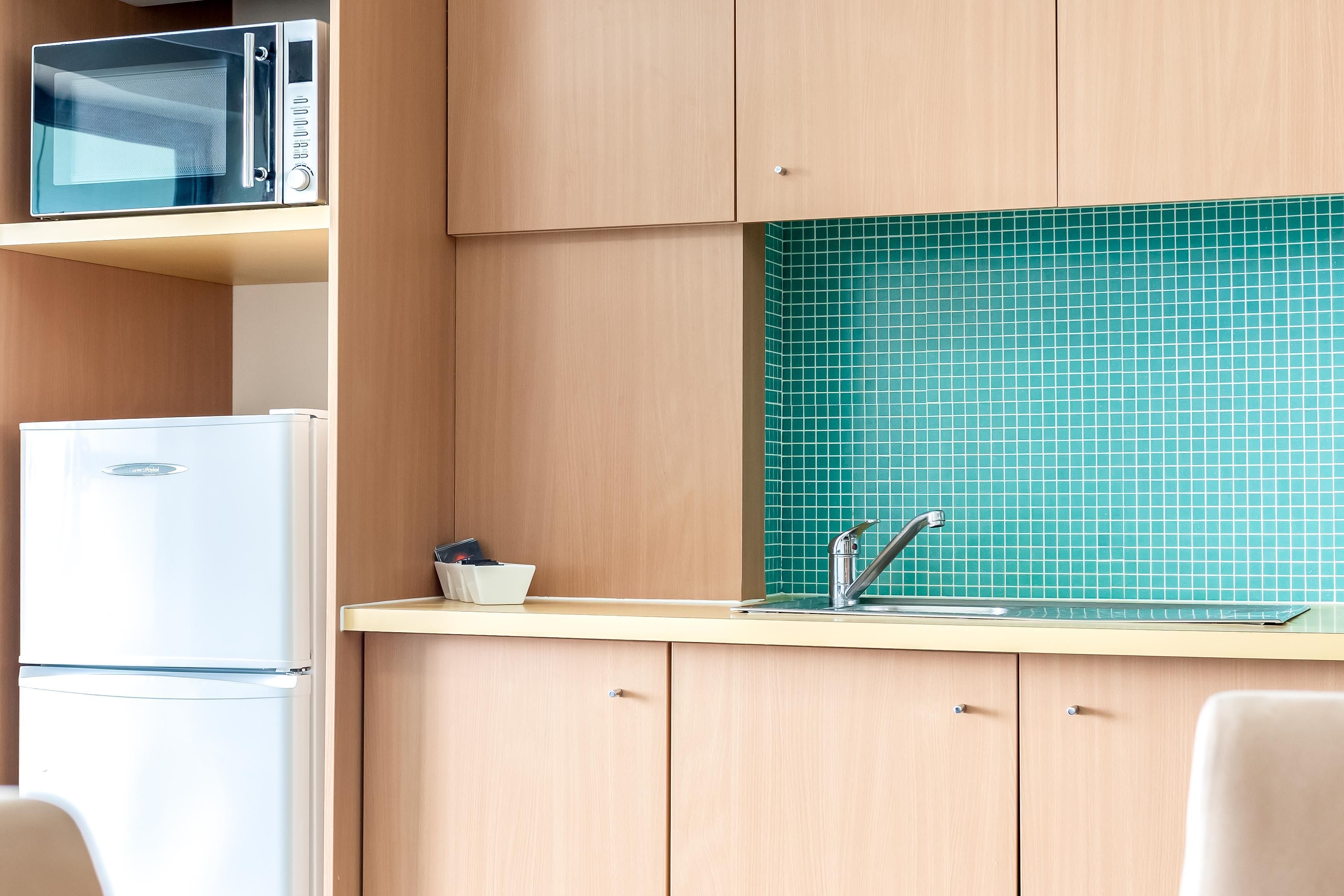 A kitchen with a microwave, refrigerator, and a sink with a faucet.