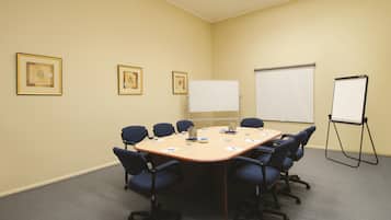 Una sala de conferències amb un gran taulell oval, sis cadires, una pissarra i tres quadres penjats a la paret.