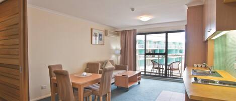 A hotel room with a dining area, kitchenette, and a balcony with a view.
