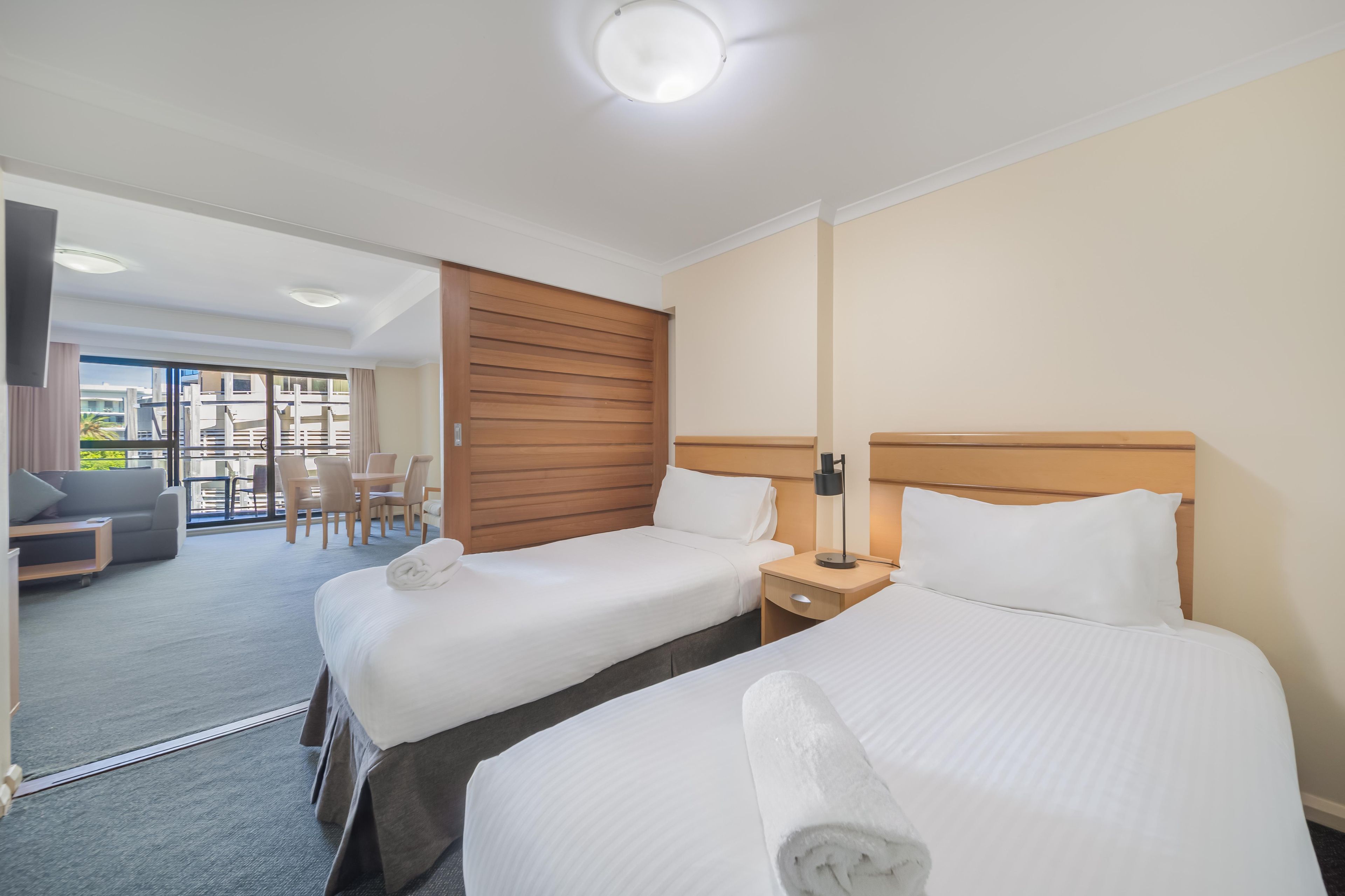 Ein Hotelzimmer mit zwei Betten, einer Sitzecke mit Sofa und Sesseln sowie Blick ins Freie.