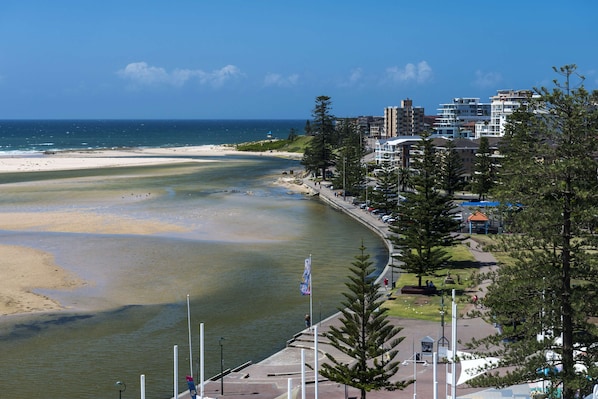 A coastal view with a beach, a promenade, and residential buildings.