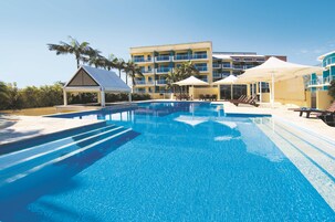 Una piscina al aire libre, sombrillas, sillones reclinables de piscina